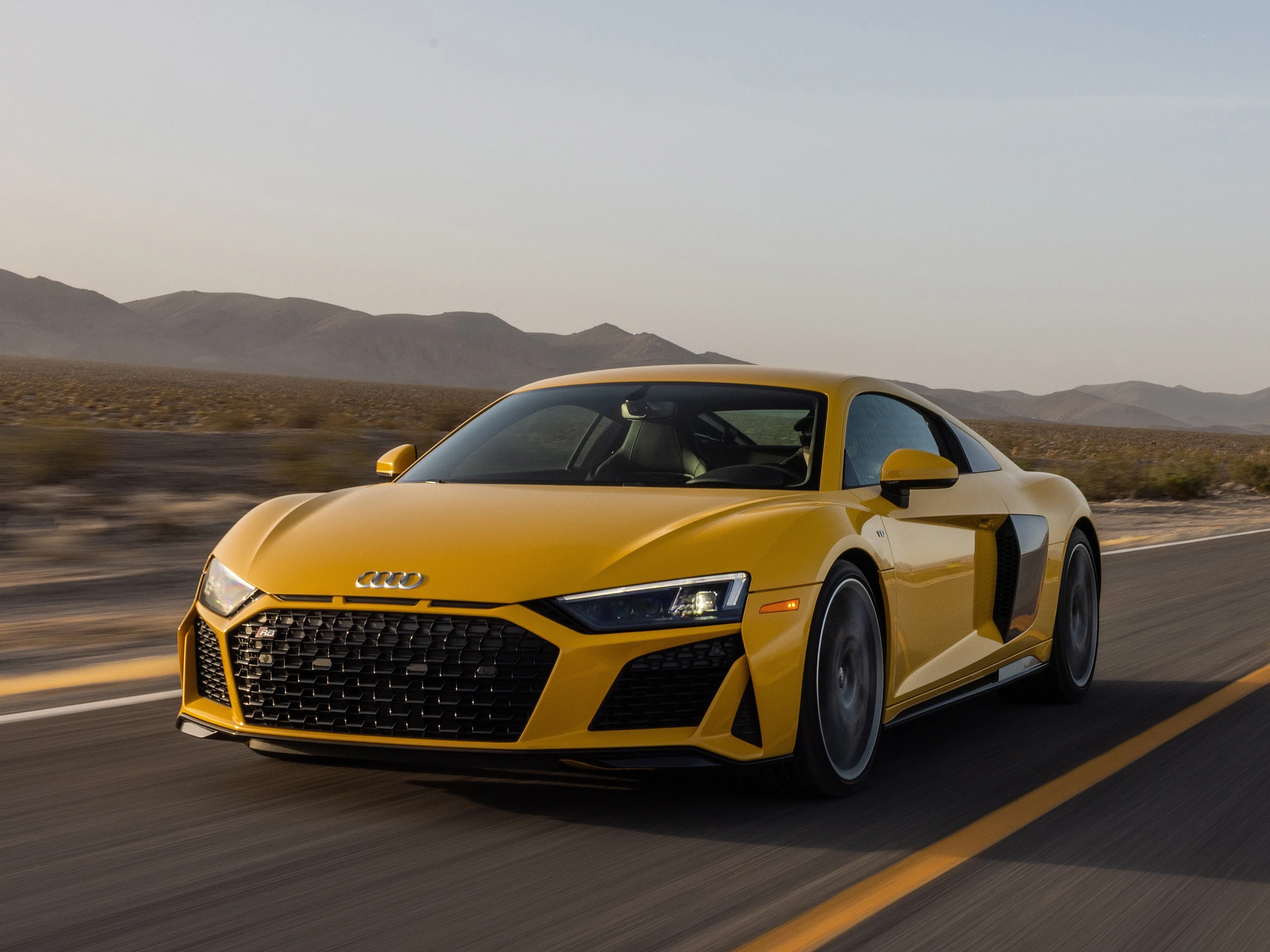 A picture of a yellow Audi R8 driving on a desert road