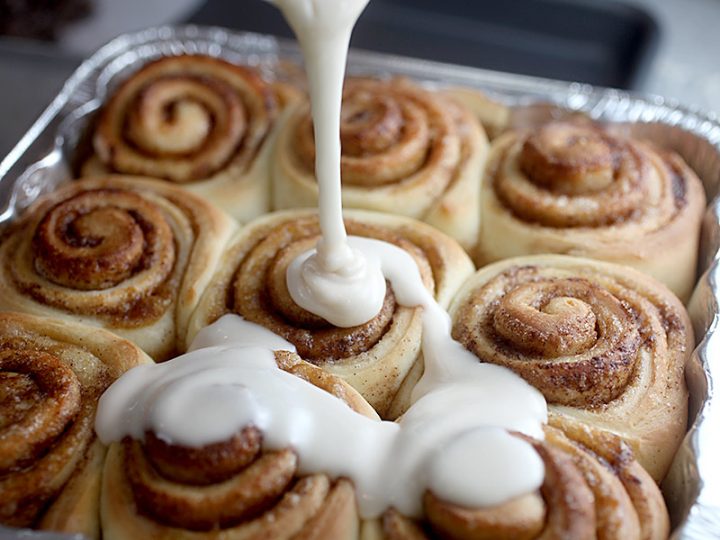 A batch of cinnamon rolls with glazing.