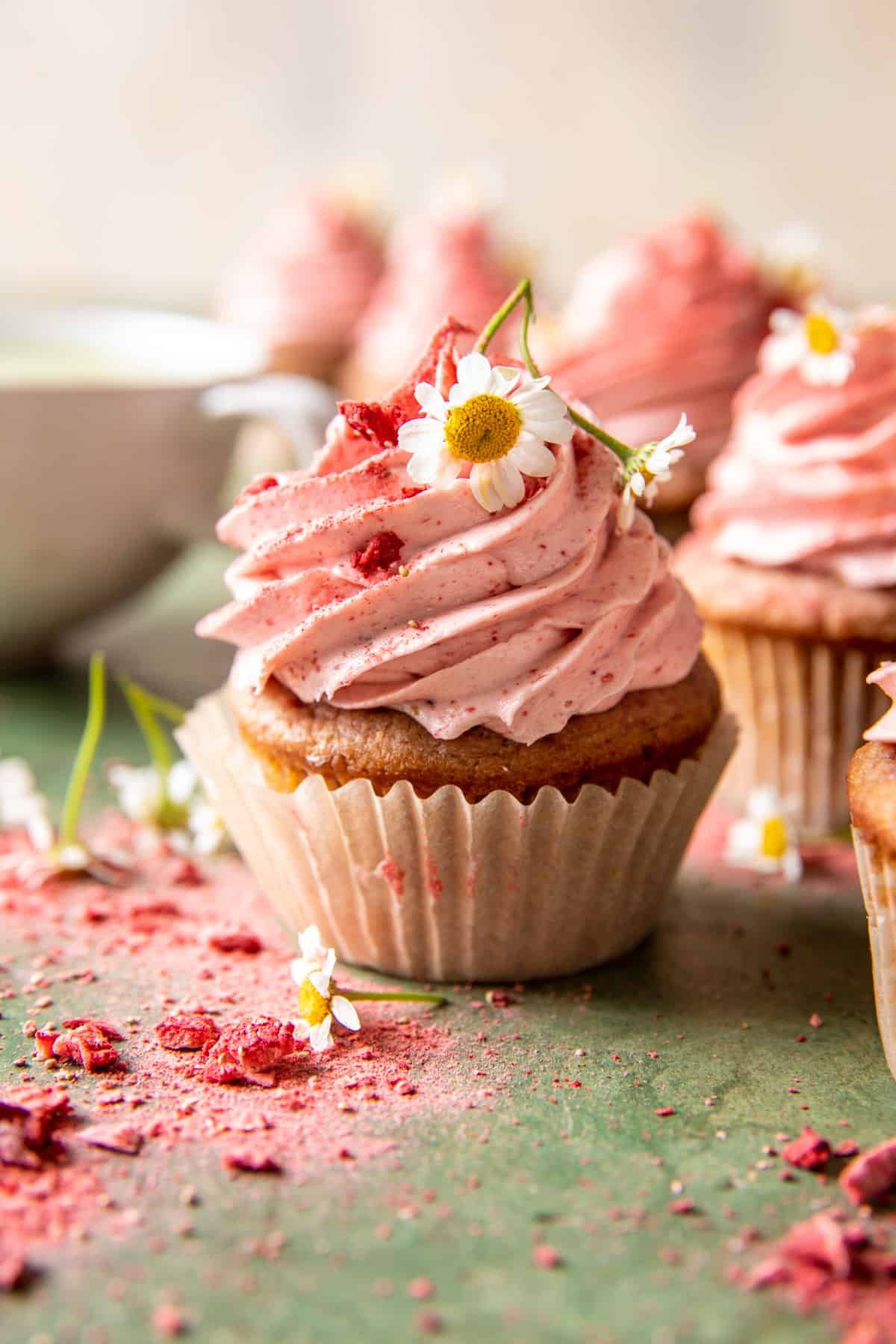 a cupcake with pink frosting and a flower on top as decoration