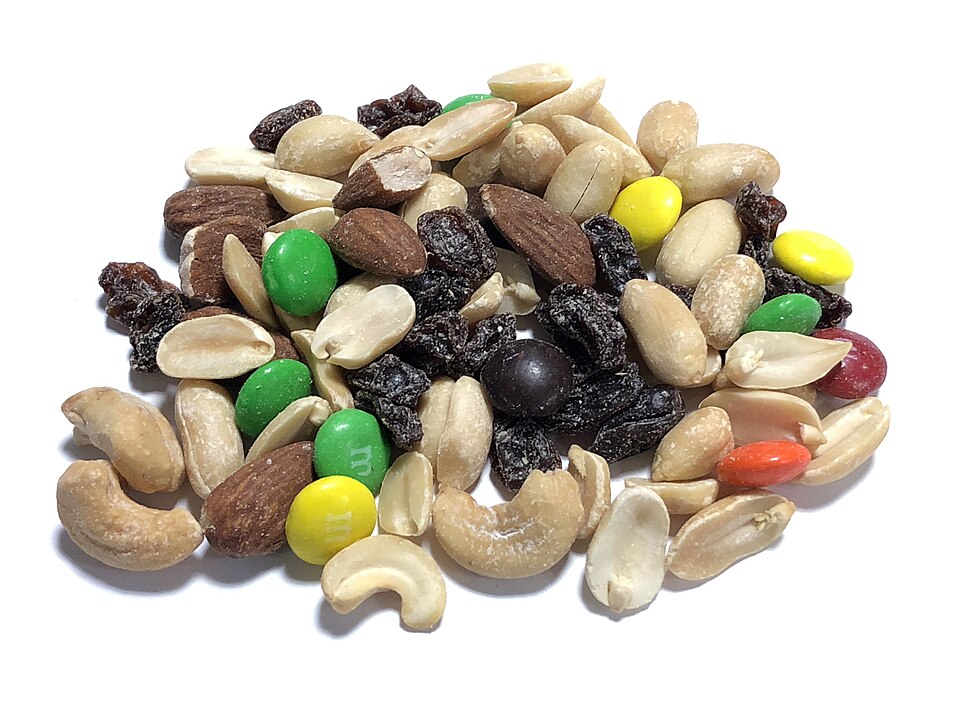 A handful mix of cashew, raisin, peanut, raisin, and chocolate, on a white background
